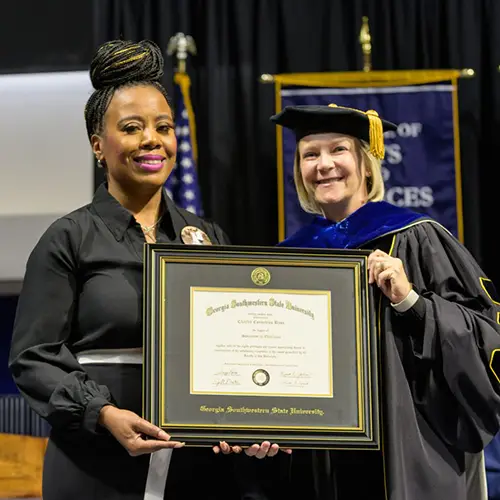 Shey Bass accepts her husband's framed degree from President Johnston