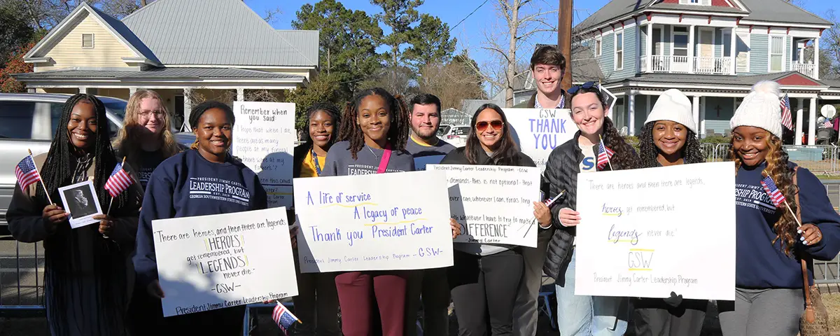 students hold signs before Carter's funeral