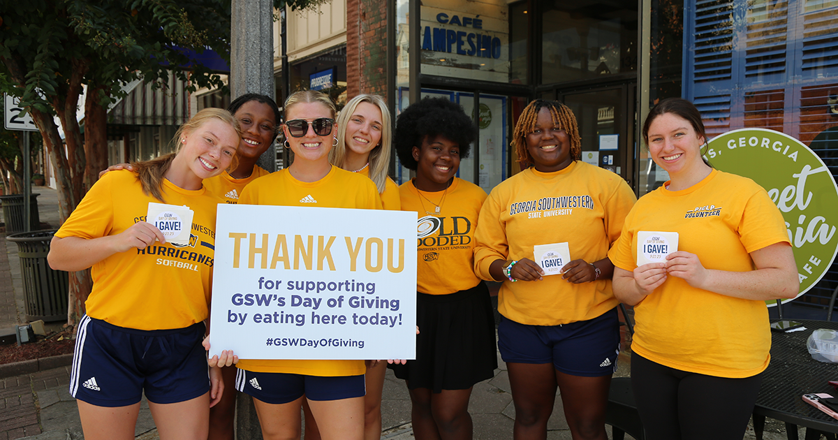 students wear gold and hold Day of Giving signs